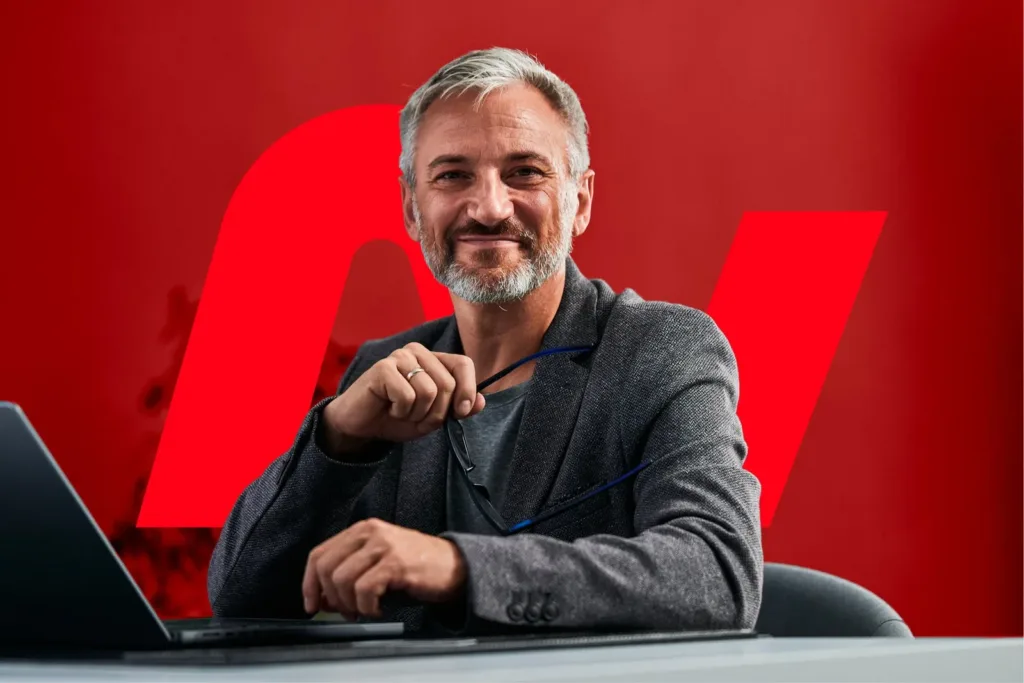 Avocat en fusions-acquisitions souriant à son bureau, logomark Avocatio en fond